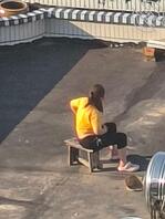 小卖店老板娘在楼顶坐着吹风，衣服都撩起来了